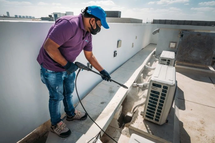 man washing the outer unit of ac
